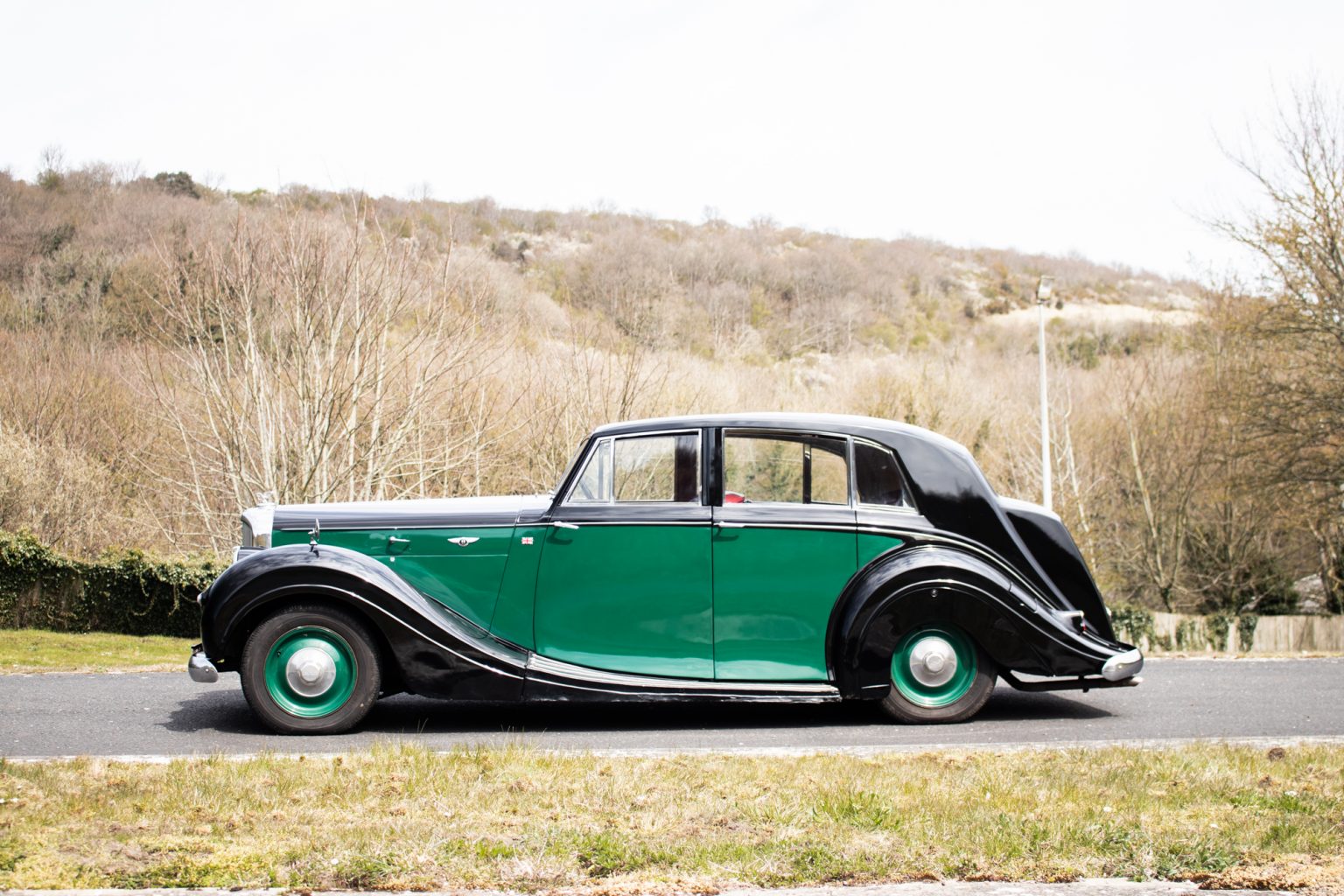 Green and black vintage Bentley saloon on a private road